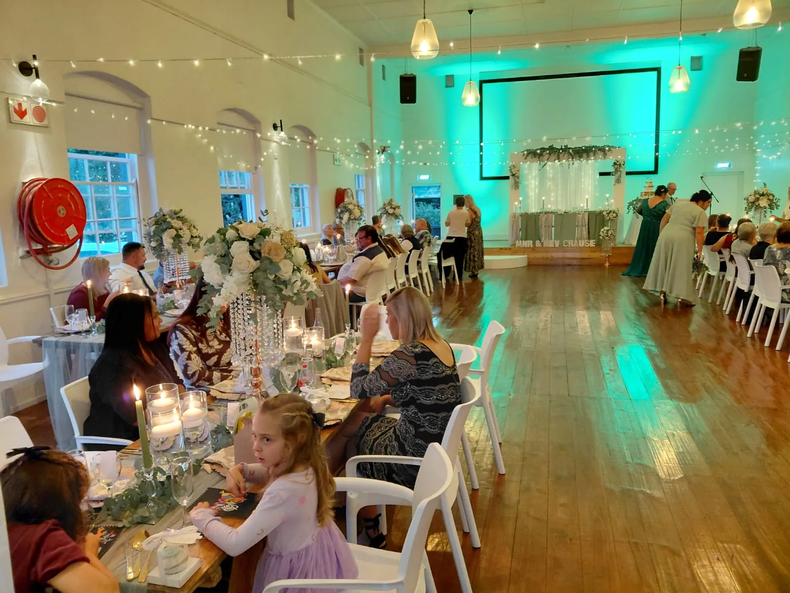 An evening reception, tables full and the room lit in teal