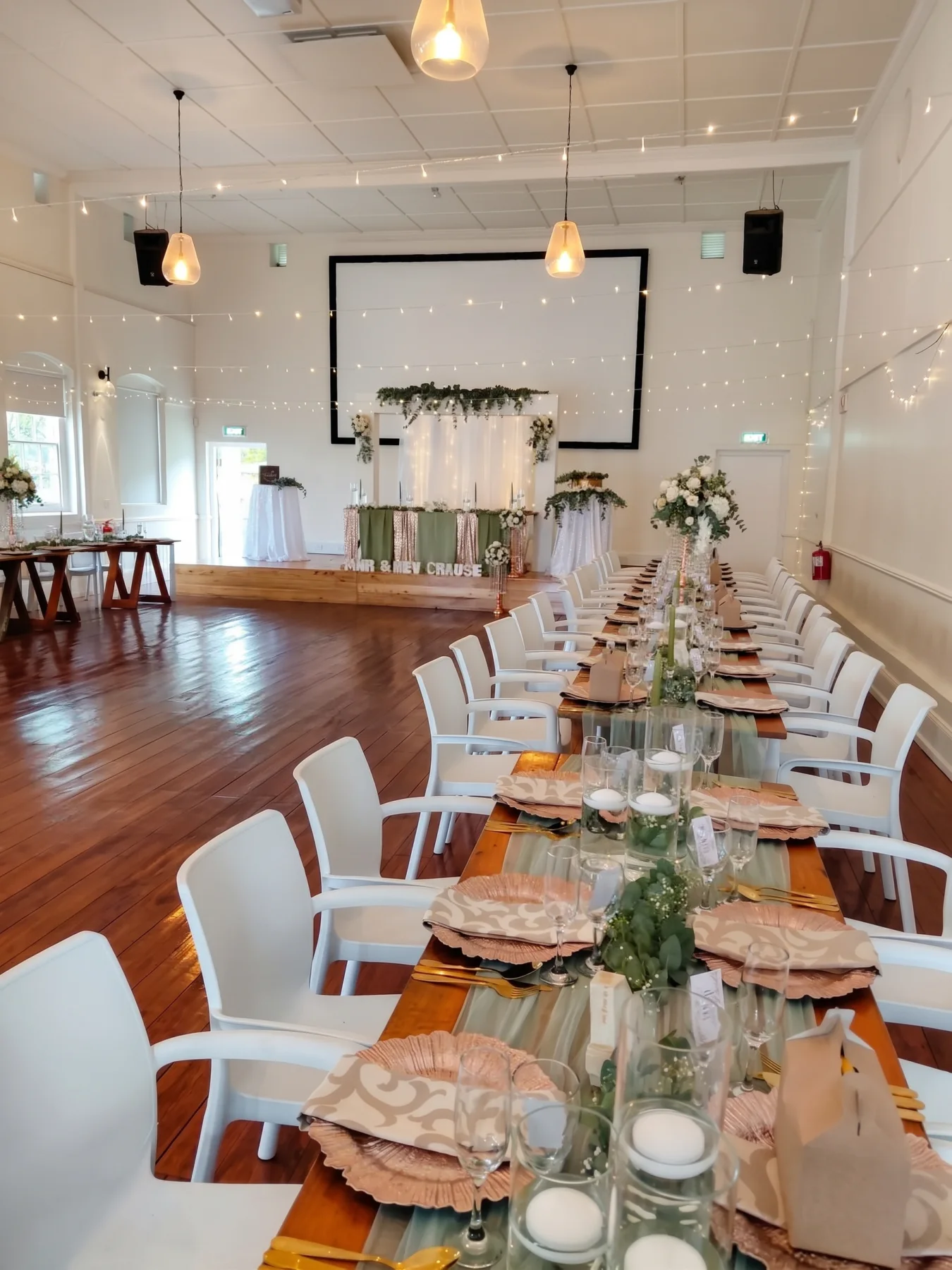 A hall laid for a banquet with the projector screen down at the far end